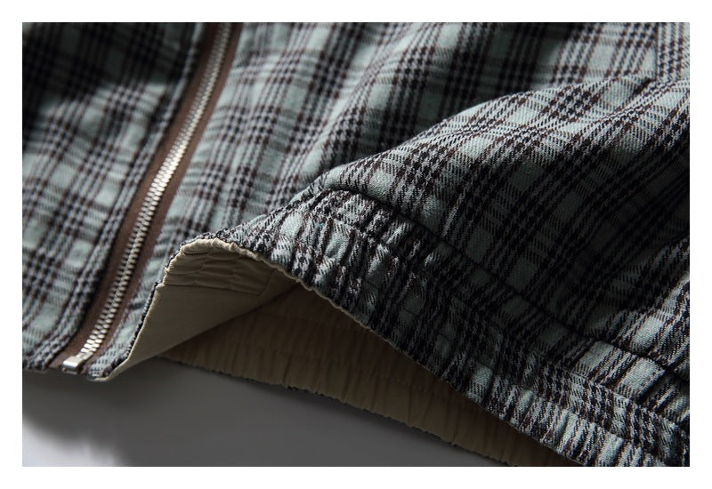 Close-up of a gray plaid garment showing a zipper, gathered seam, and beige lining.