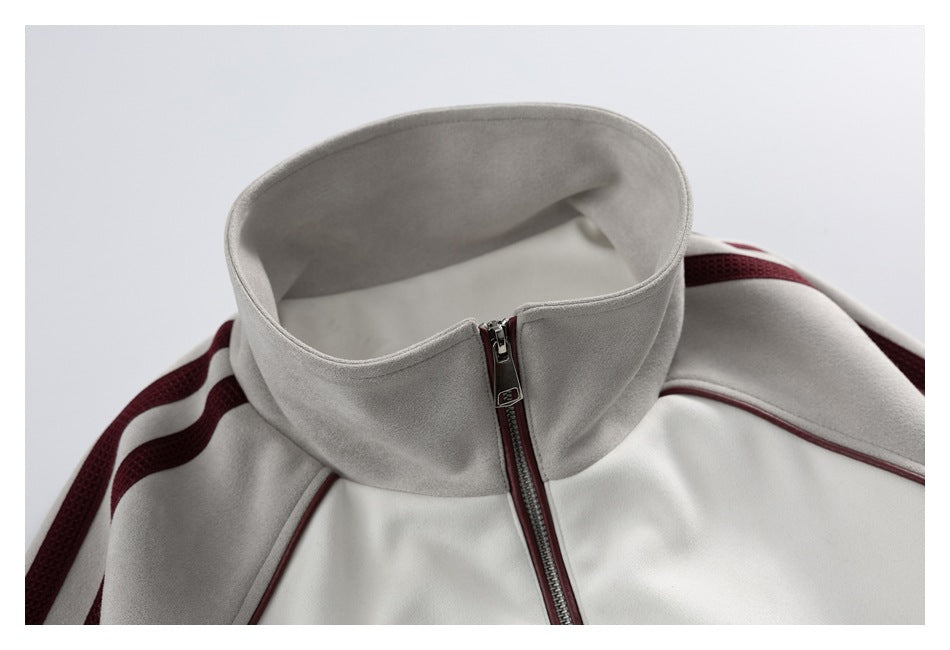 Close-up of an ivory and light gray jacket with a burgundy front zipper and tall stand collar.