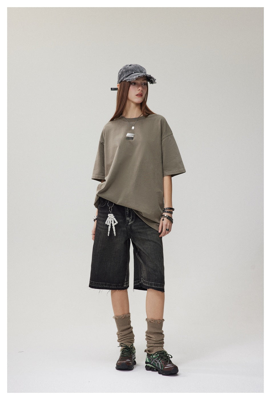 Full-length model wearing an oversized olive taupe T-shirt and black knee-length denim shorts.