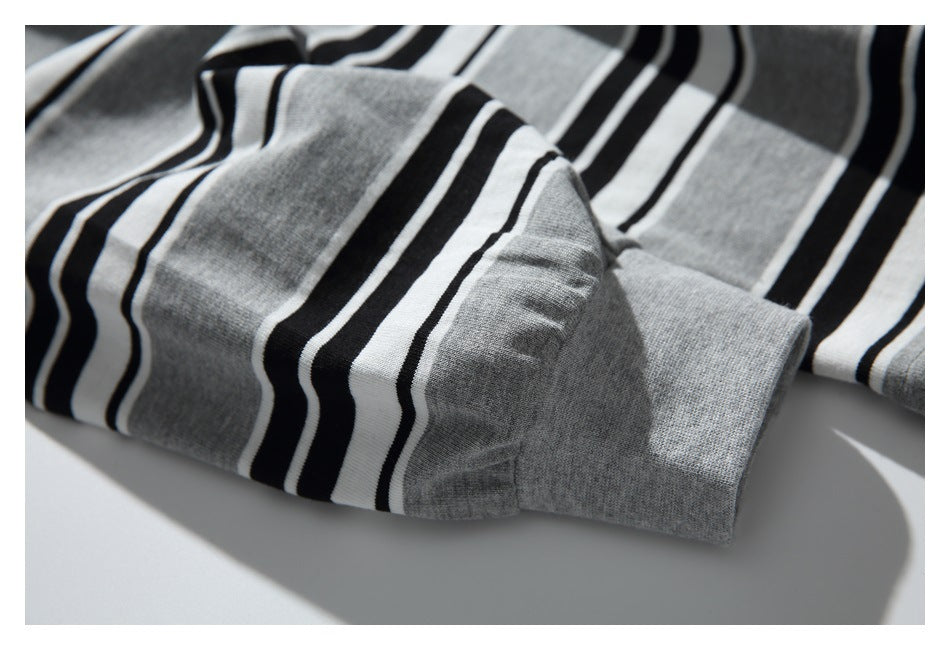 Close-up of a gray, black, and white striped knit garment with a wide solid-gray cuff.