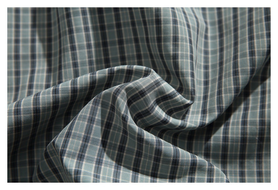 Close-up of draped blue-gray plaid fabric with dark and light intersecting stripes.