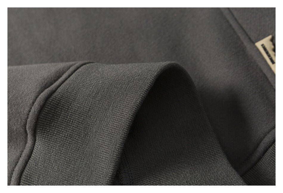 Close-up of a dark charcoal ribbed cuff beside a small sewn-in garment label.