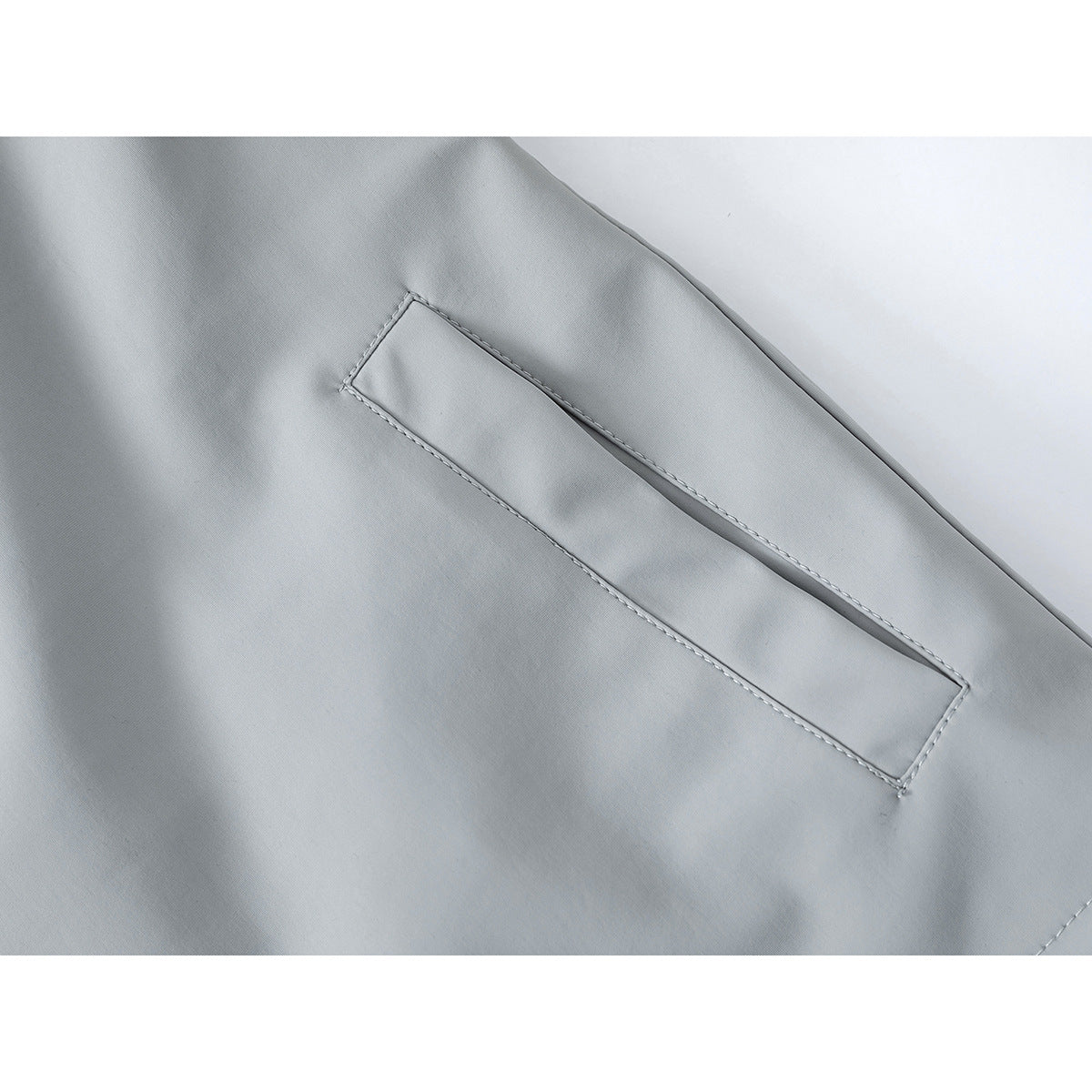 Close-up of a narrow welt pocket on a light gray jacket.