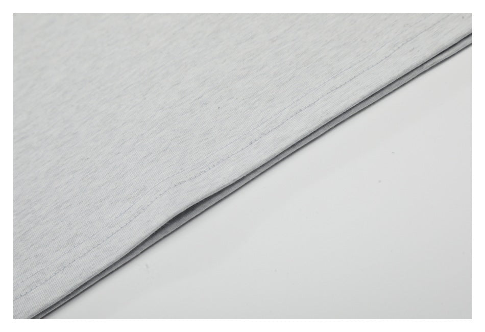 Close-up of the double-stitched bottom hem on a light gray T-shirt.