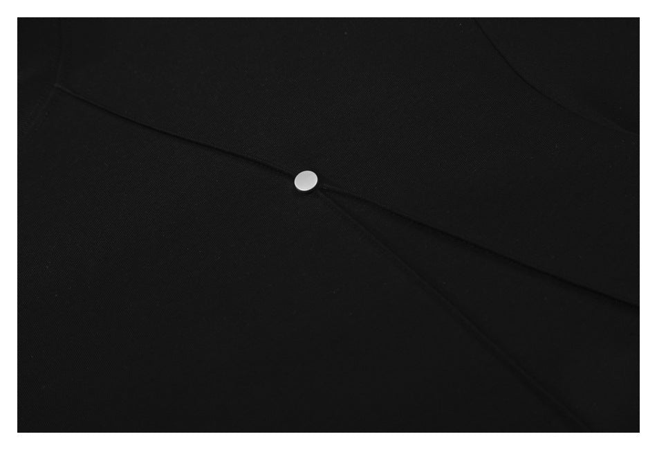 Close-up of a black garment with intersecting stitched panels and a small silver snap fastener.