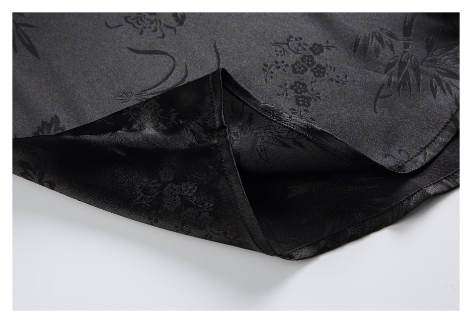 Close-up of black fabric with a subtle floral pattern, showing a curved stitched edge and folded hem.