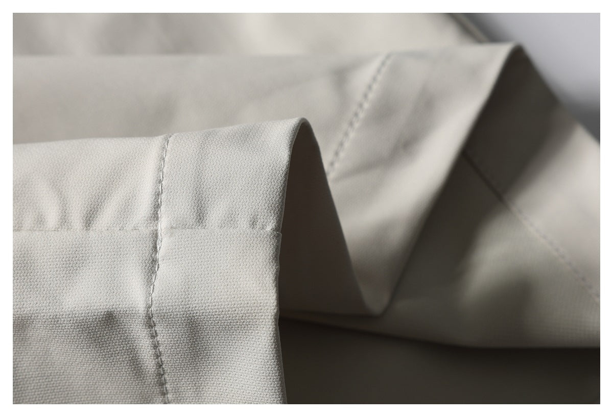 Close-up of light beige pants fabric folded to show a stitched edge and seam.
