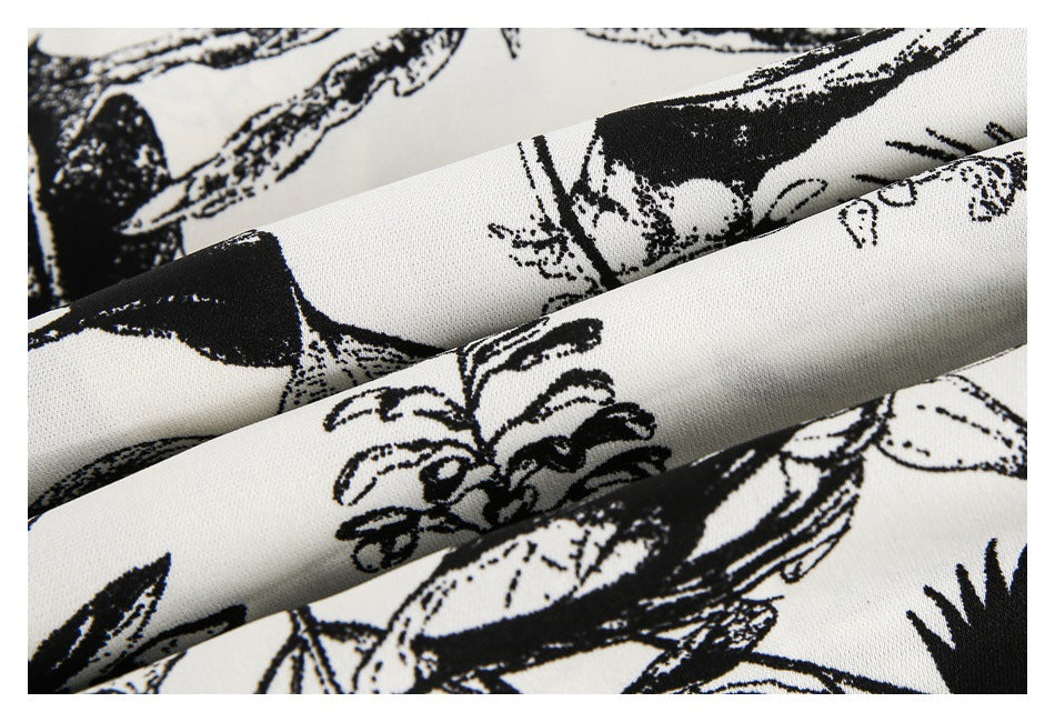 Macro view of folded ivory fabric with a black botanical print and visible surface texture.