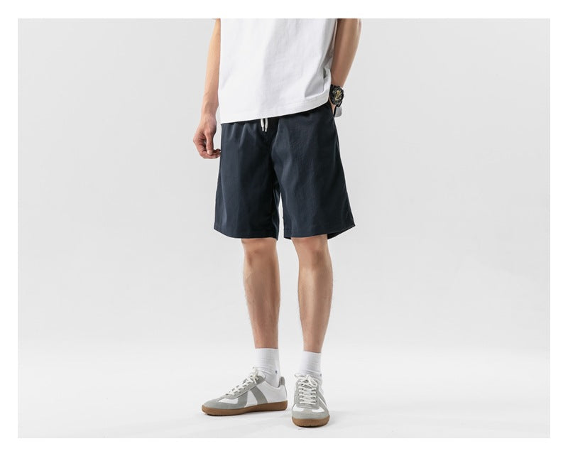 Model wearing navy knee-length shorts with a white T-shirt and sneakers, three-quarter view