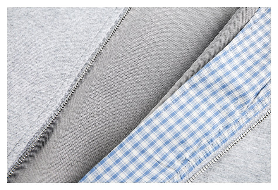 Close-up of a gray zip-front garment showing the zipper and blue-and-white checked inner lining.