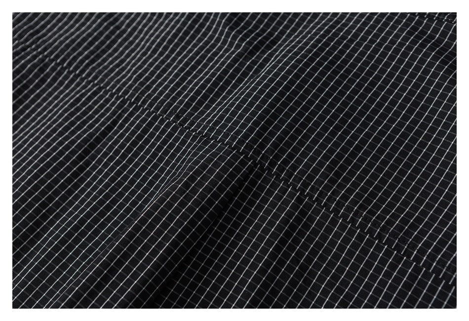 Close-up of black grid-patterned fabric with a diagonal stitched seam.
