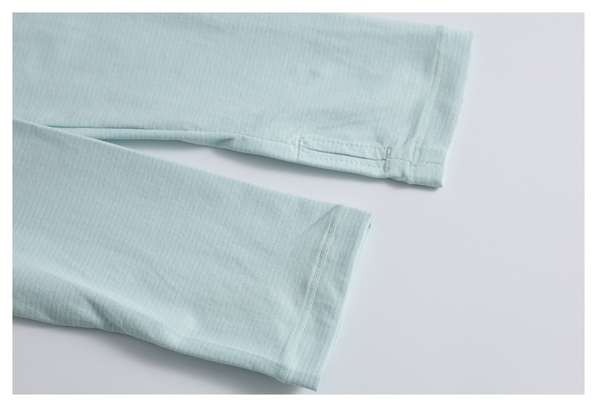 Close-up of pale aqua fabric cuffs with stitched hems and a small buttonhole.