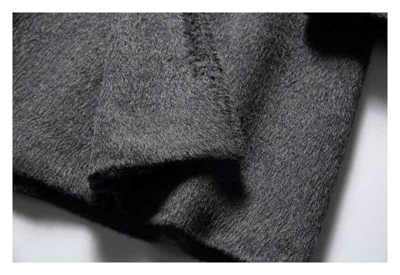 Close detail of a charcoal gray coat pocket opening and surrounding seams.