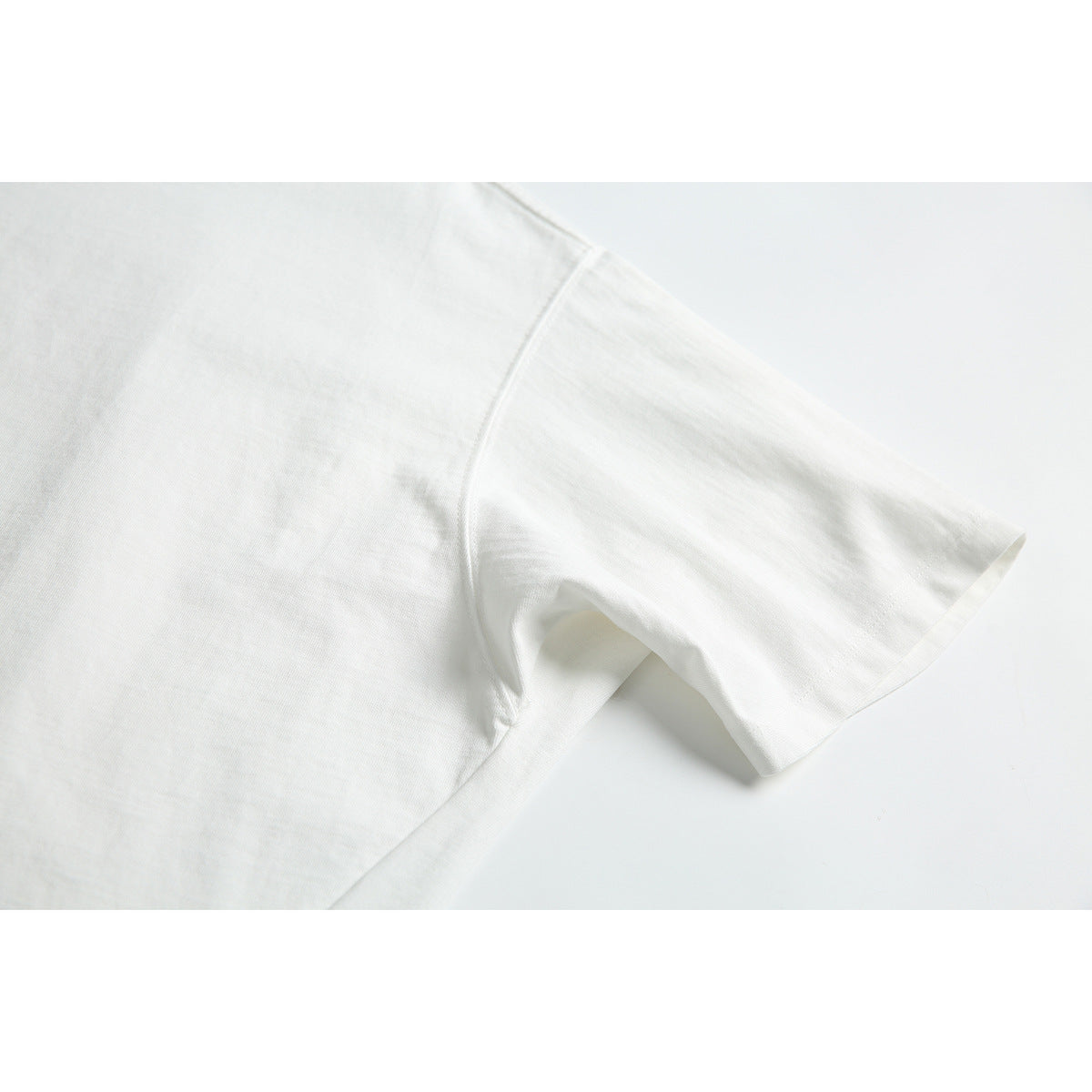 Close-up of a plain white T-shirt sleeve and underarm seam.
