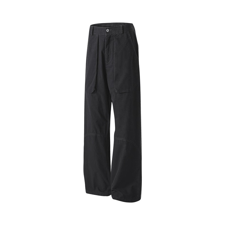 Angled front view of black wide-leg trousers with a button waist, large front pockets, and curved knee seams.
