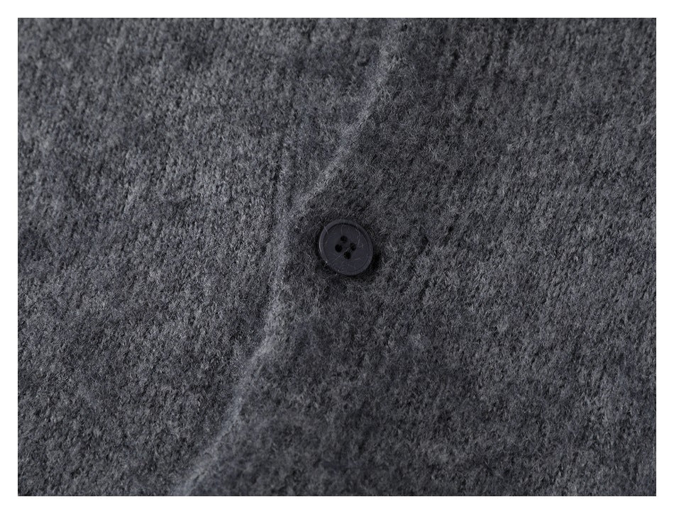 Close-up of a dark button on the charcoal gray knit cardigan's front placket.