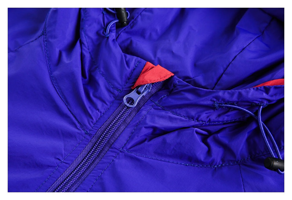Close-up of a blue jacket's front zipper, red trim, and adjustable hood drawcord with toggle.