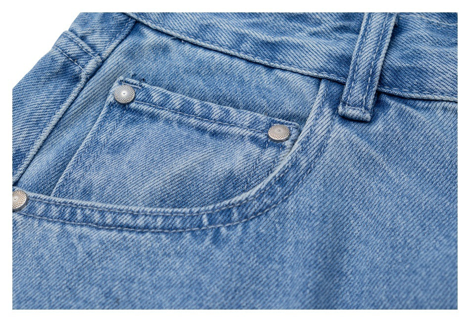 Close-up of light blue jeans showing the waistband, belt loop, front pocket and riveted coin pocket.