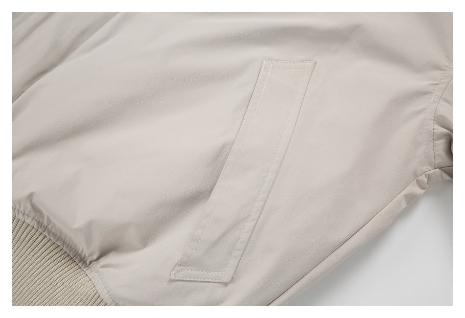 Close-up of a vertical welt pocket on a light beige garment.