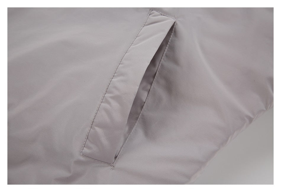 Close-up of a long angled welt pocket on a light gray garment.