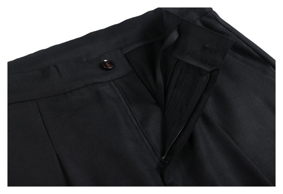 Close-up of black trousers with the waistband undone, revealing the button, fly, and zipper.