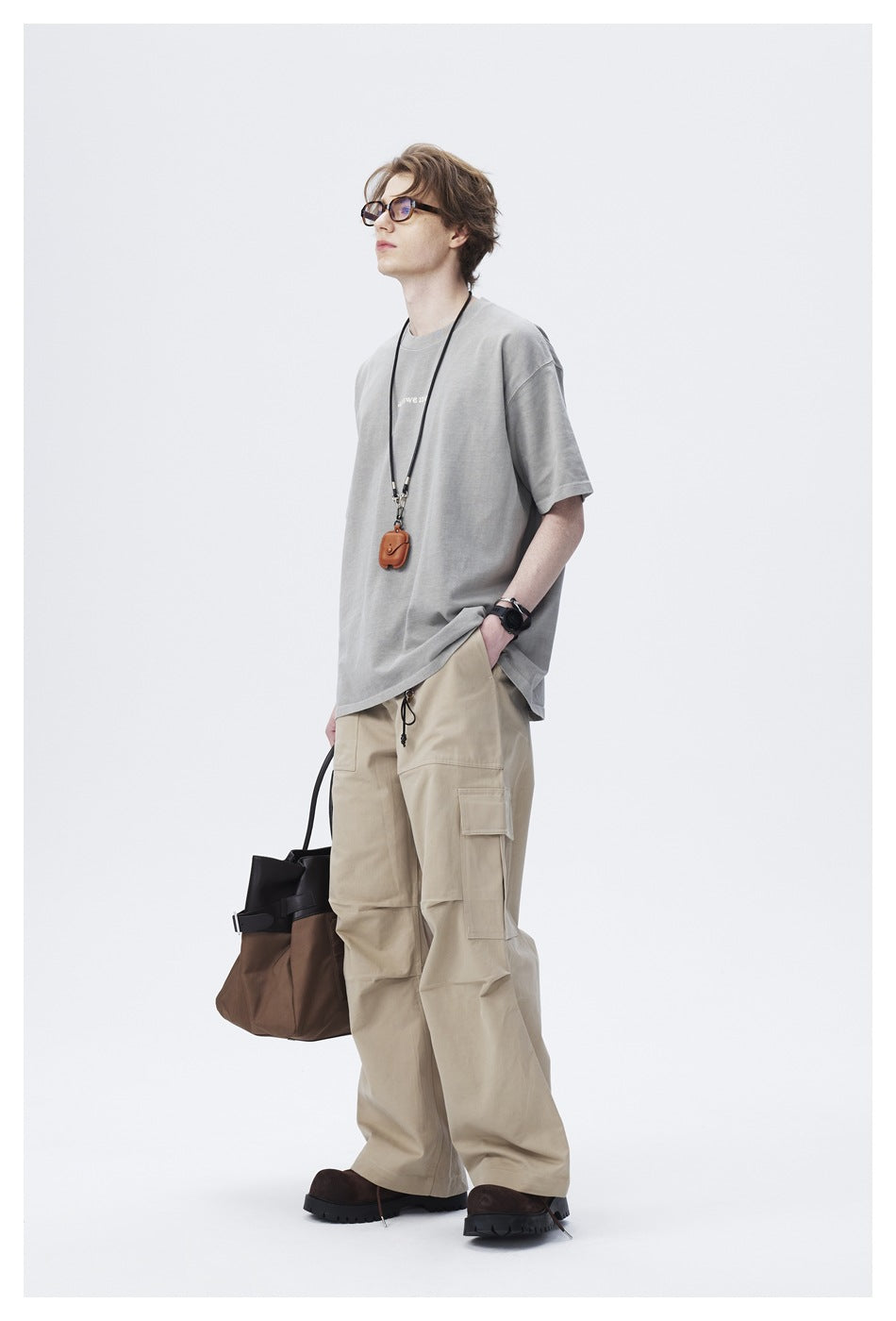 Model in gray oversized t-shirt and khaki cargo pants, angled side view with hand in pocket