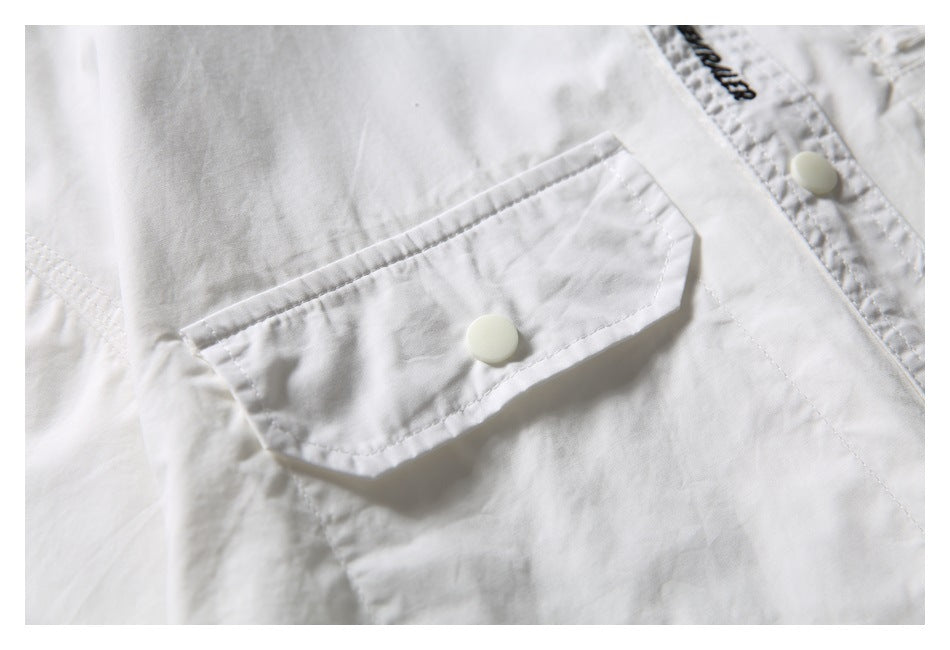 Close-up of a white flap chest pocket with a snap button on the shirt.