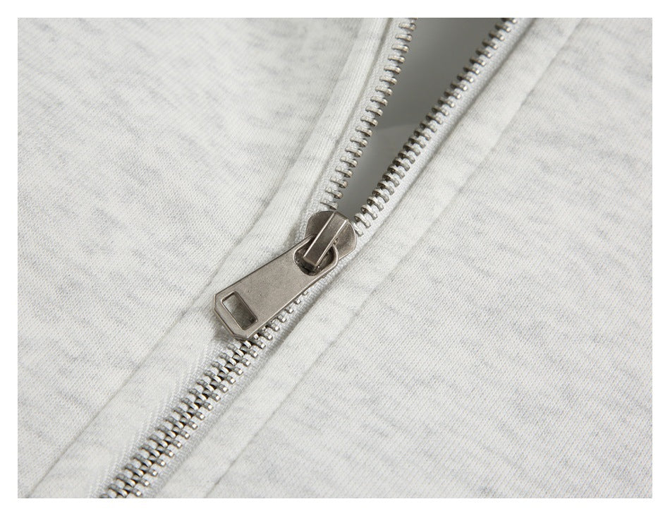 Close-up of a silver metal zipper on light gray marled fabric.