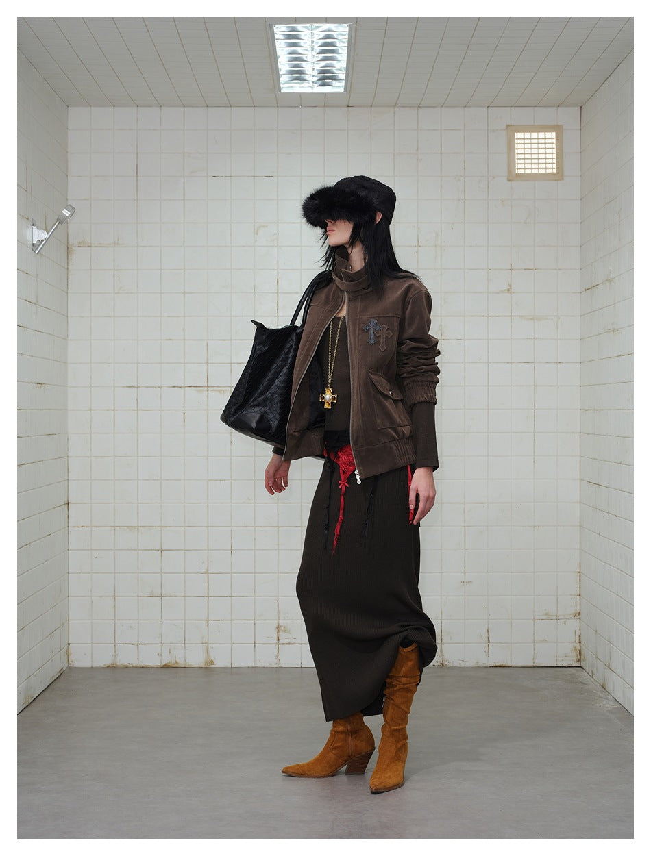 Side view of a model in the brown jacket showing chest cross patches, flap pocket and elastic cuff, with black bag and boots