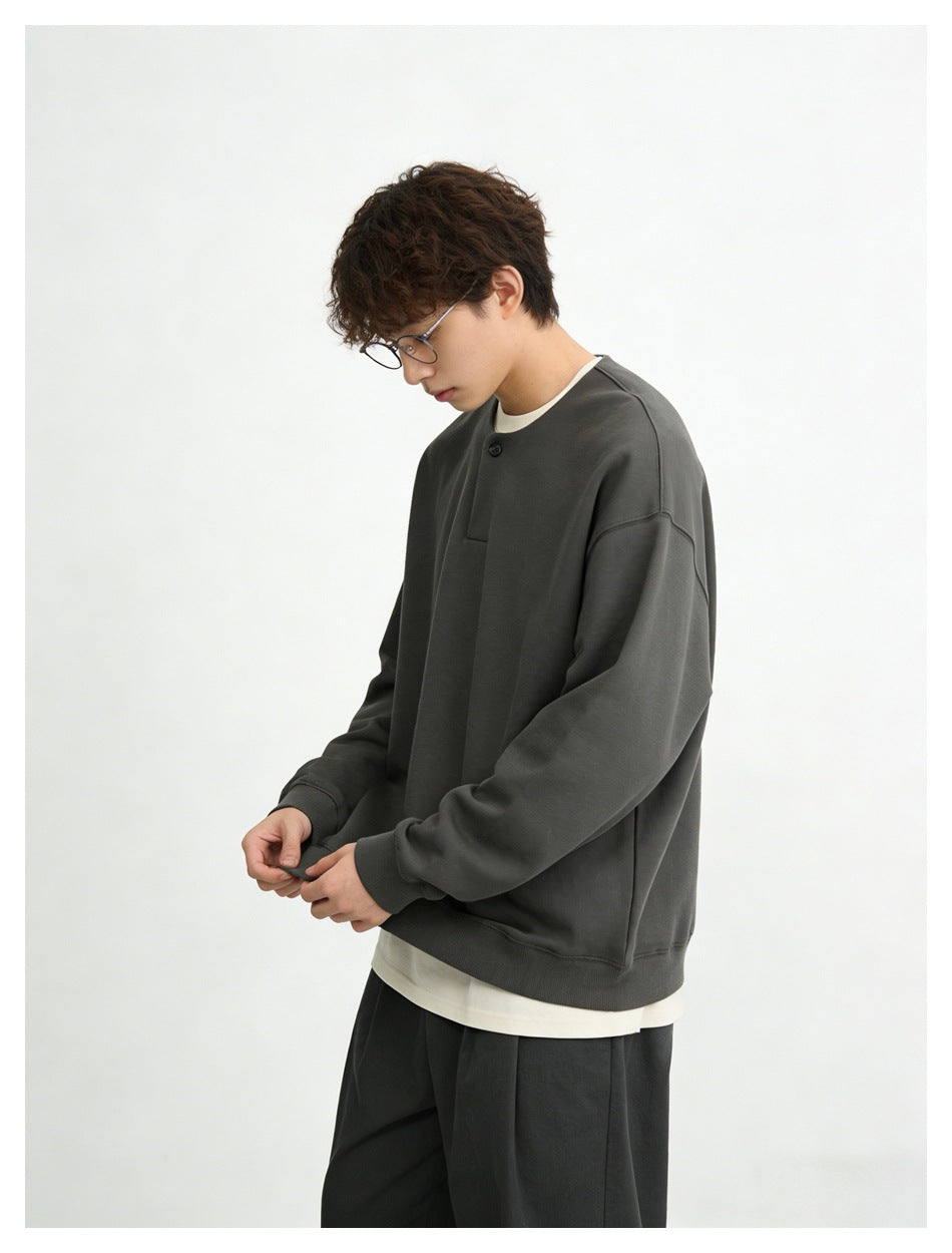 Model in a charcoal oversized sweatshirt with a short button placket, shown at an angle.