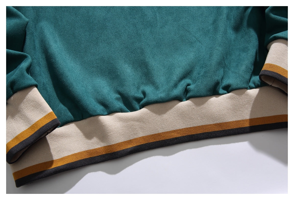 Close-up of a teal garment's cream hem and cuffs, each striped with mustard and charcoal.