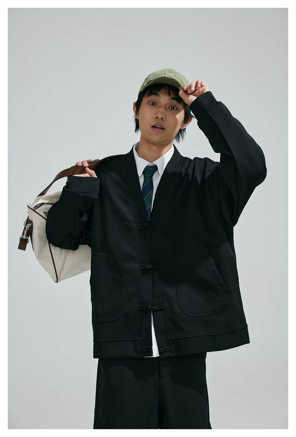 Closer front view of a model wearing a black jacket with toggle closures, large patch pockets and ribbed cuffs.