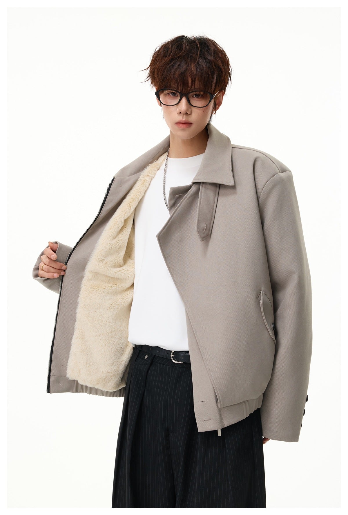 Model wears an open taupe jacket revealing cream sherpa lining, over a white shirt and pinstripe trousers.