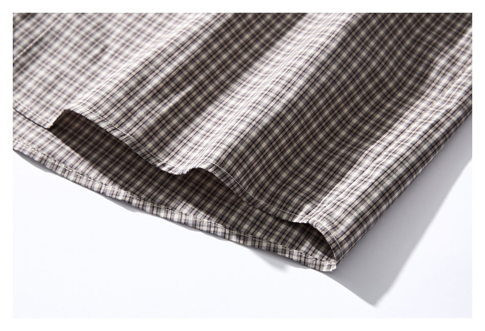 Close-up of the stitched hem on a gray and cream small-check shirt.