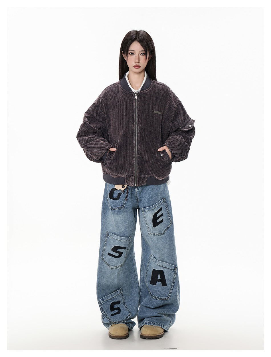 Model wearing a dark brown ribbed zip-front bomber jacket with dropped shoulders and blue patchwork jeans.