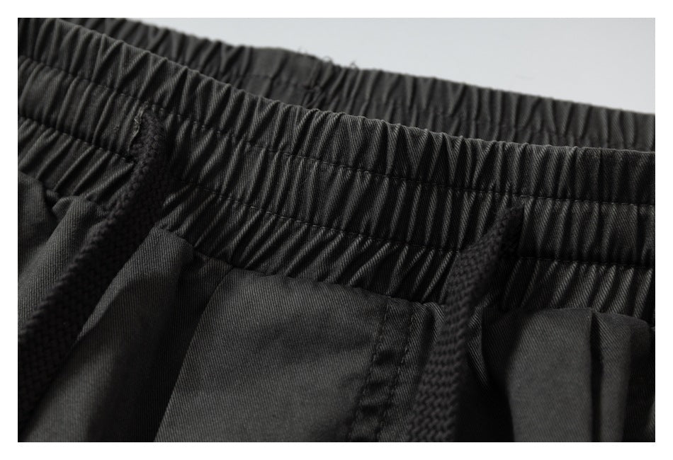 Close-up of charcoal pants with a gathered elastic waistband and black drawstrings.