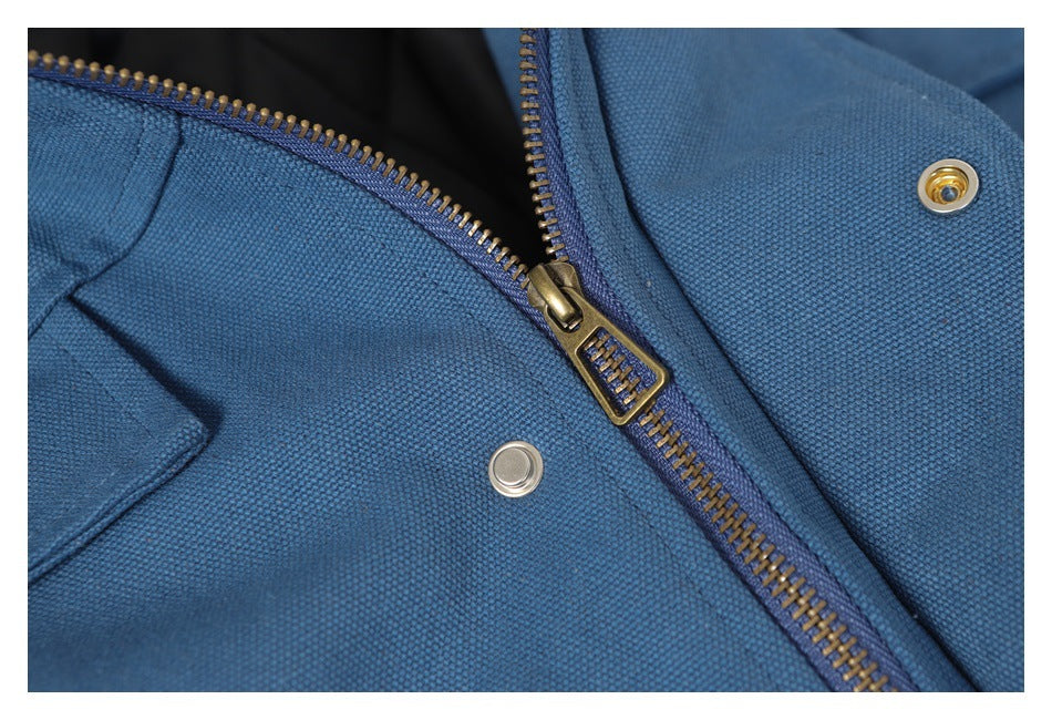 Close-up of a blue jacket with a brass-colored zipper and two metal snaps.