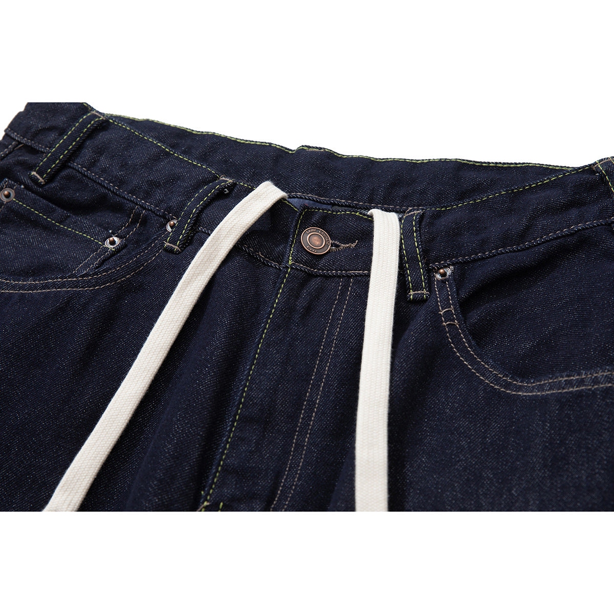 Close-up of dark indigo jeans at the waist, with belt loops, a metal button, contrast stitching, and white drawstrings.