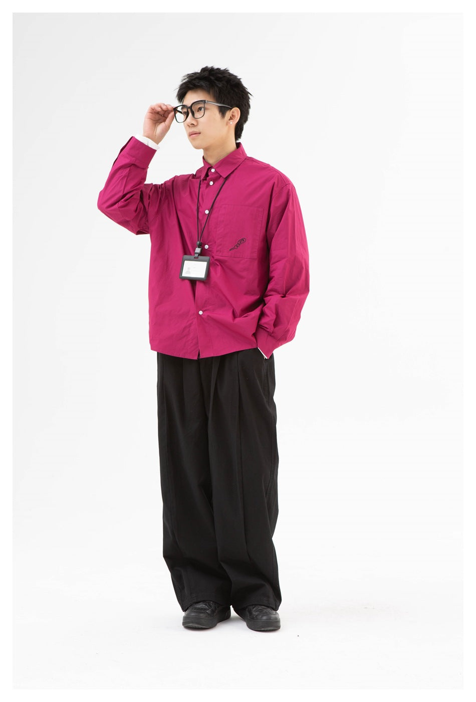 Full-length three-quarter view of a model wearing a magenta button-up shirt and wide black trousers.