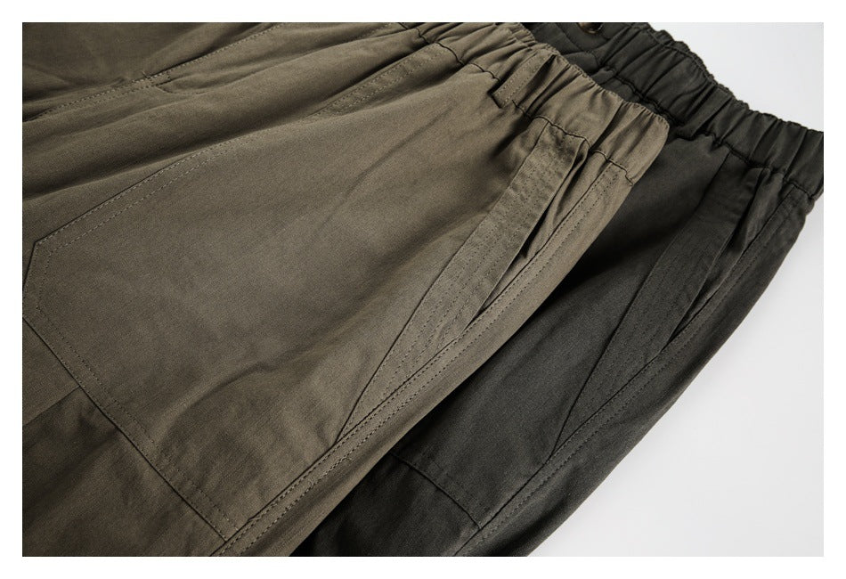 Close-up of overlapping olive and charcoal trousers showing pocket seams and gathered waistbands.