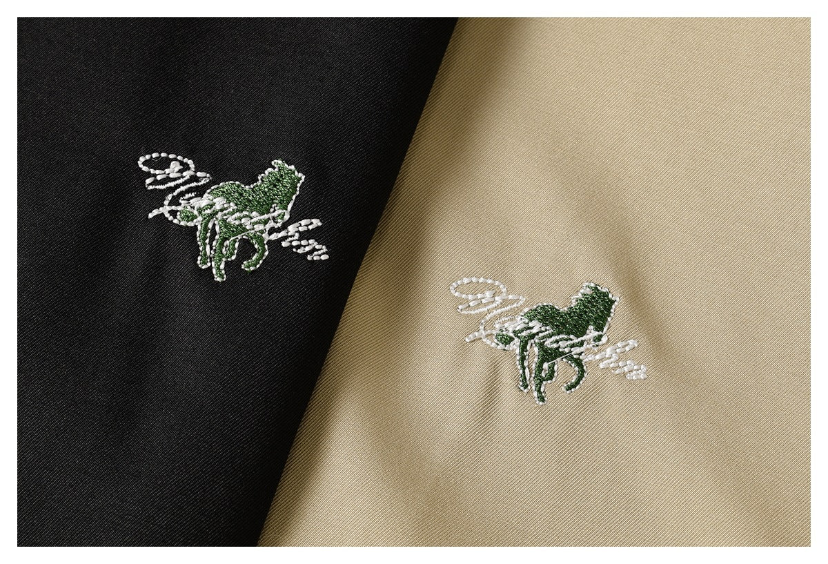 Close-up of white and green embroidered motifs on black and beige fabric.