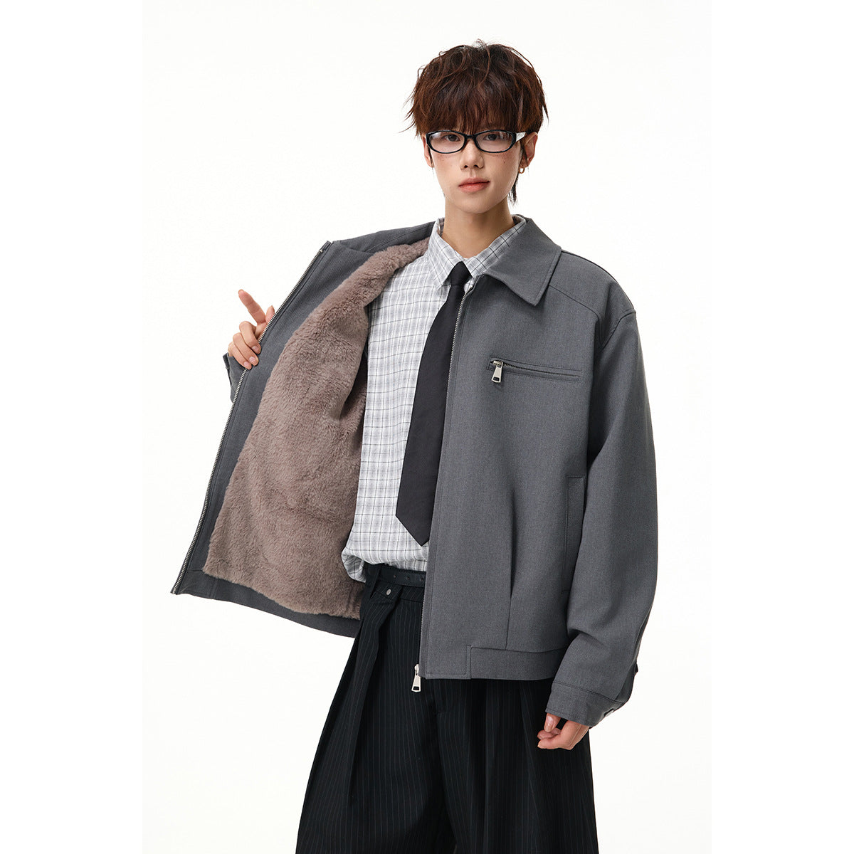 Model wearing a charcoal zip jacket open to show plush lining, over a checked shirt and tie.