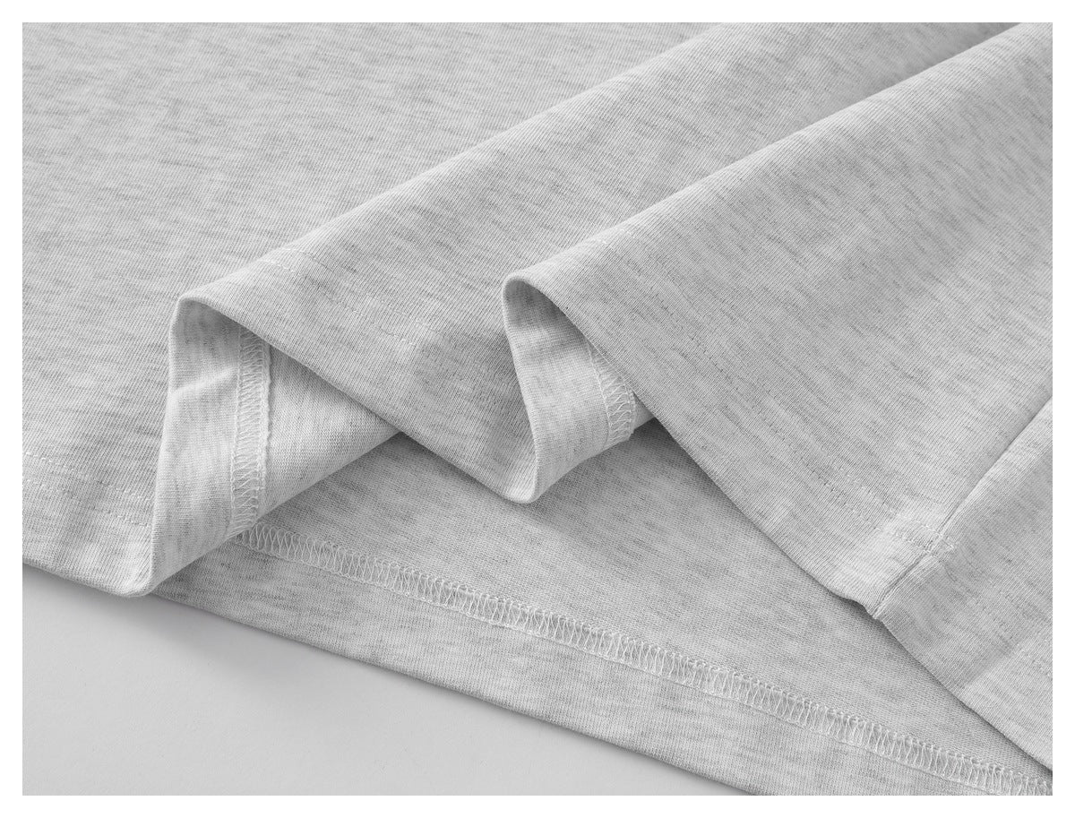 Close-up of the light gray shirt's folded hem and overlock stitching.