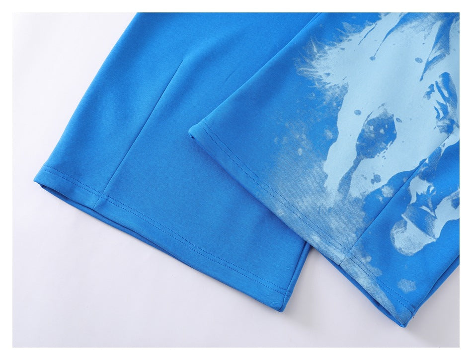 Close-up of bright blue pants showing a pale abstract print and double-stitched hems.
