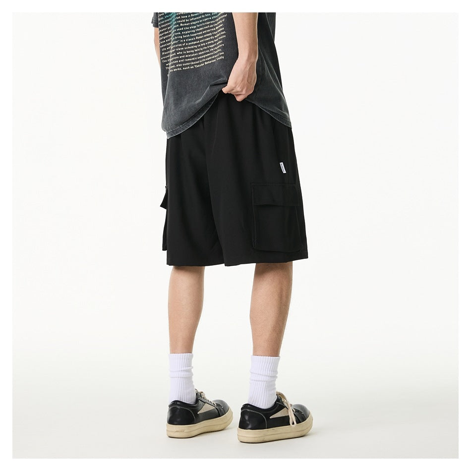 Rear three-quarter view of a model wearing black cargo shorts with a large flap pocket; the T-shirt has English text.
