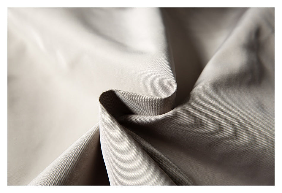 Close-up of light beige fabric draped into folds, showing its fine surface texture.