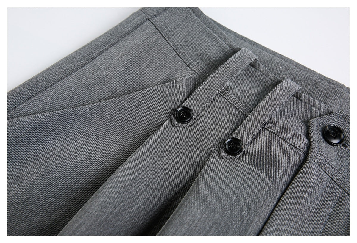 Close-up of gray trouser waistband and belt loops with black buttons.