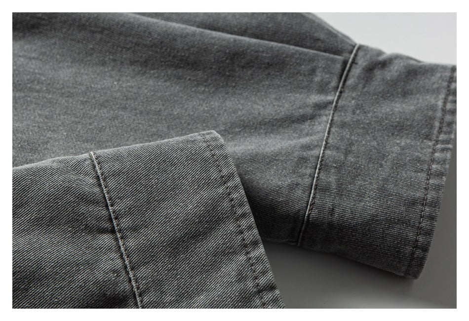 Close-up of a dark gray garment sleeve and stitched cuff, with the cuff turned back.
