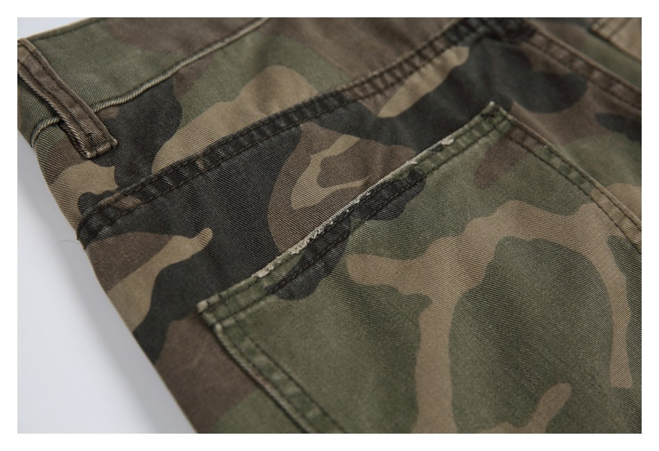 Close-up of olive, brown, and black camouflage trousers showing a belt loop and stitched pocket.