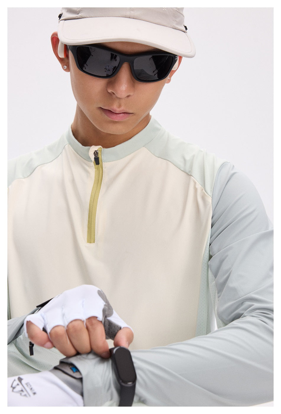 Close-up of a man wearing a cream quarter-zip top with pale sage shoulders and sleeves.